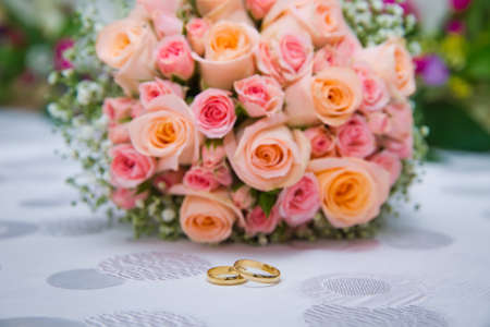 Bridal bouquet with orange and pink roses of different size with handle on white background.の写真素材