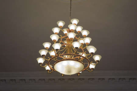 Beautiful hanging Vintage lamp with yellow light. luxury expensive chandelier hanging under ceiling in palace.の写真素材