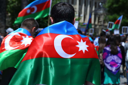 Azerbaijan flag in Baku, Azerbaijan. National sign background. The boy put a flag on his shoulder.. Azerbaijan tradition patriotic. Flags waving windの写真素材