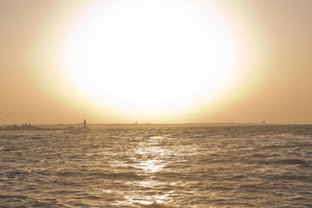 The fisherman fishes in the sea . Beautiful sunset at the beach, amazing colors, light beam shining...