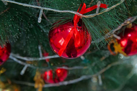 red and gold ball hangs on the background of a clock. It's time for a new year. Multicolored glare...
