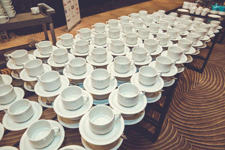 Close up dirty coffee cup and spoon setting on white saucer and wooden table after drinking in the morning in vintage style.の写真素材