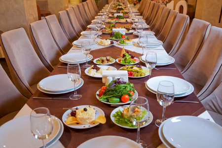 Food on the table in the restaurant . Tablet set service with silverware and glass at restaurant before party . Served holiday table, cutlery, crockery, glasses, plate, fork. Salads and gumsの写真素材