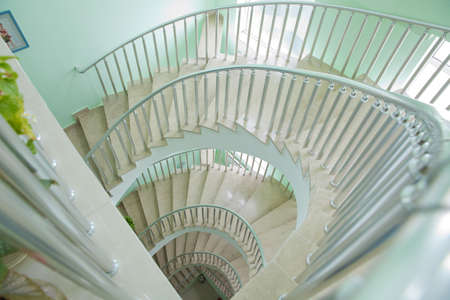 Spiraling steps . Circular Staircase. Spiral staircase from bottom view with white cement wall...