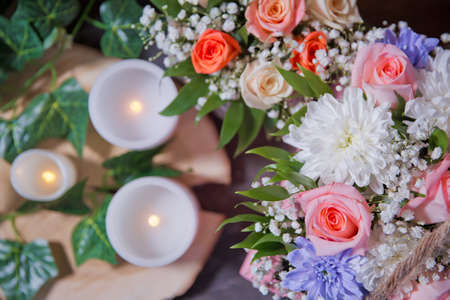 Multi-colored flower bouquet, candles in the background. White , Pink roses, purple and candles on white candles background. Selective focus.の写真素材