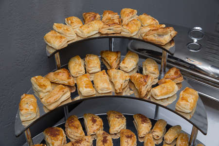 Pies with meat, cabbage or any filling. Baked pies in the oven. On a white plate and a peach color...