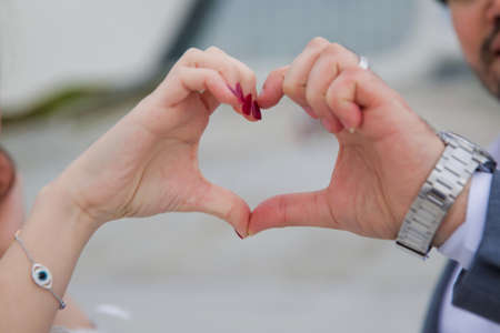Heart-shaped hand On the bokeh background . The teenager folded her hands in the shape of a heart against the background .Happy couple making heart with their hands outdoorsの写真素材