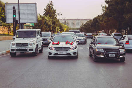 Street as a part of wedding cortege . Wedding cortege in the Baku city centre. wedding cortege at the head of the car. Red and white flowers bouquet . Closeup image of wedding car decoration . Road.の写真素材