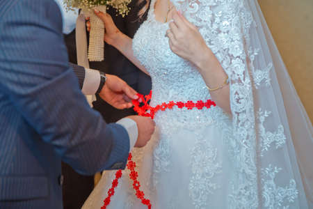 Close the ribbon on the belly of the bride . Lose the ribbon on the belly of the bride . Wedding . Bridesmaids lace bride . Close the ribbon on the belly the brideの写真素材