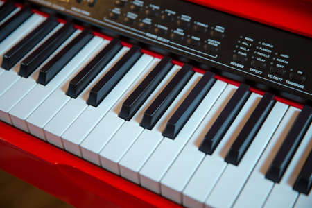 Red piano keyboard with glossy black and white keys as a music background in wide panoramic banner...
