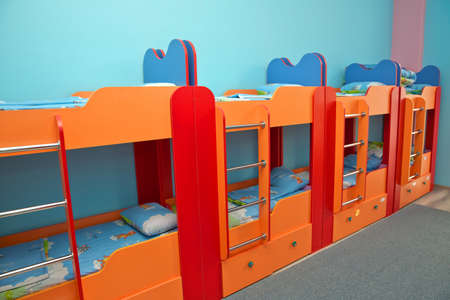 Rest in a public kindergarten. Many beds in the bedroom. Empty room . Beds in bedroom for kids . Private kindergarten or nursery bedroom . Interior of a kindergarten bedroom with two-level bedsの写真素材