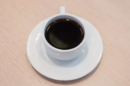 coffee beans in white porcelain cup decorated wild herbs . white cup, coffee in white sauce.Cup of...