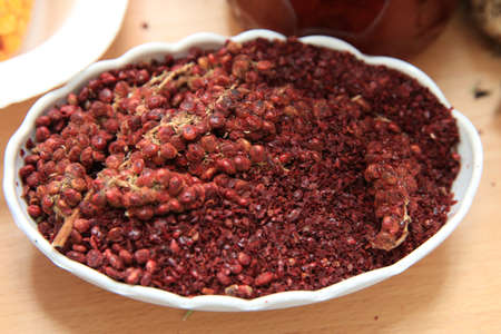Dried sumac seasoning in a wooden bowl, top view. a handful of red sumac powder in a plate abstract...