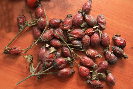 Pile of dried rose hips . Pile of dried red fruits of the dog rose on the light-colored wooden rustic table . Hawthorn on wooden rustic table background. Rose hips haw fruit of the dog rose.の写真素材