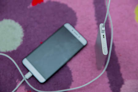 Smartphone charging with power bank on pink carpet . Phone charging with energy bank . Smartphone...