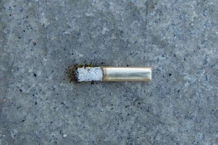 Smoke and ashes on the pavement. Cigarettes in gold . cigarette end on the pavement . Discarded cigarette on the street. Environmental pollution. Cigarette butts on the roadの写真素材