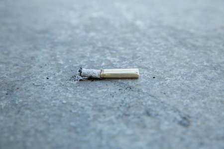 Smoke and ashes on the pavement. Cigarettes in gold . cigarette end on the pavement . Discarded cigarette on the street. Environmental pollution. Cigarette butts on the roadの写真素材