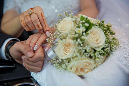 Wedding couple holding hands .Bride and groom hands with wedding rings and bridal dress . Bride and groom's hands with wedding ringsの写真素材