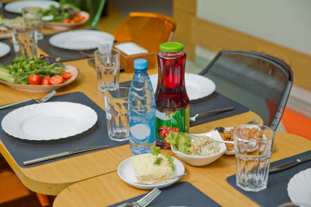 A children's table in the restaurant. Plate fork, knife, glass. Kampot drink. Tomato cucumber and steak salad.の写真素材