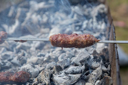 Shish kebab on a metal stick, top view. Lula kebab on skewers , traditional Caucasian dish, close-up . Appetizing lula kebab grilled on metal skewer.の写真素材