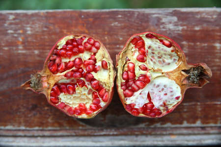 Red pomegranate, divided into two parts, on a wooden table. high in vitamin . Top view of...