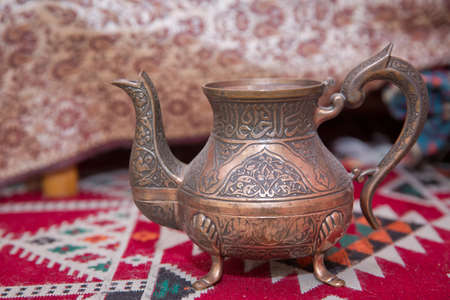 Copper teapot . Copper bowl . vintage oriental teapot on a background of carpet .Beautiful vintage copper teapot kettle with tarnished metal, sitting background of carpet. Old teapot with abrasions.の写真素材
