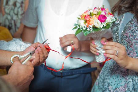 Cut the ribbon with the scissors . Wedding couple holding hands .Bride and groom hands with wedding...