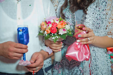 Bride and groom hands with wedding flowers and bridal dress . Bride and groom's hands with wedding flowers . The bride holds the blue in her hand, the red bakal in the bridal .の写真素材