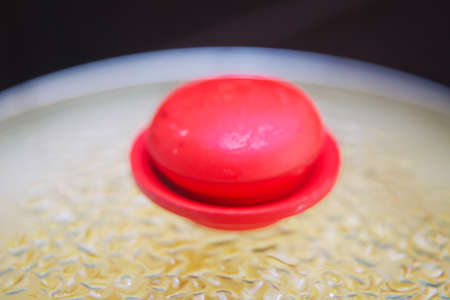 Cooking in frying pan with cover on stove . Hot pan with food covered with a glass lid that sweats...