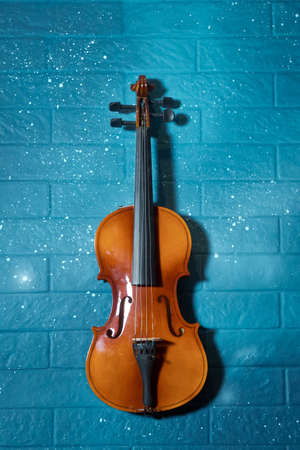 Red and brown Violin and tar blue in the background.Violin in front of blue brick wall .Classical music concert poster with orange color violin on blue background with copy space for your textの写真素材