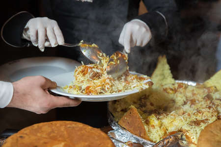 Shah pilaf. Khan pilaf in a pita. Traditional oriental dish on tableware Azerbaijan with fire on a table in restaurant .the chef cuts off the drill and puts it on the plateの写真素材
