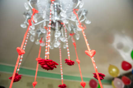 Artificial red heart and roses hanging from the laurel. A red ribbon shades out of Chandelier. Engagement decor .の写真素材