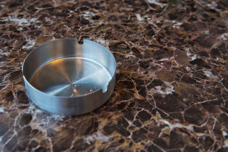 Clean empty round white glass ashtray on an old table in a park. Close up, selective focus, shallow...