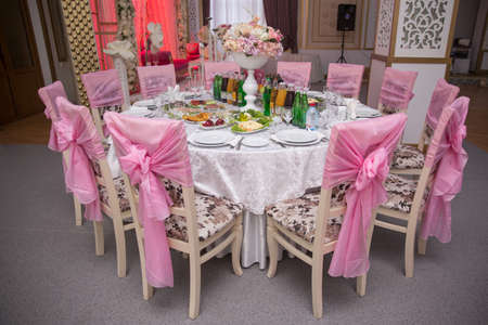 luxury wedding decor with flowers and glass vases with jewels on round tables. arrangements of...