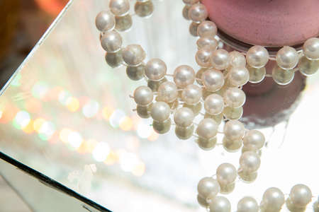 ball pearls for jewelry making spread out on the surface of the mirror.The opposite of the pearls is...