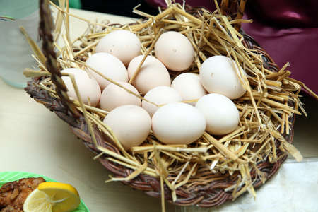 Basket of white eggs on wooden table . eggs in a wicker basket . Easter eggs. White eggs in basket. Closed up . Yellow and white egg yolkの写真素材
