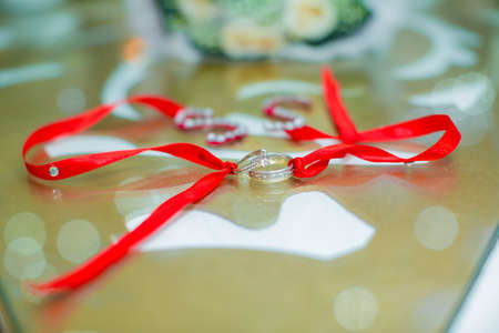 Bride and groom with Engagement gold rings put on the table .White wedding rings . flower bouquet...