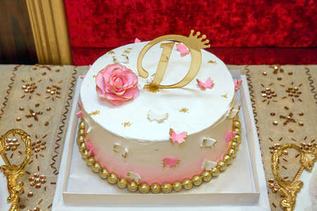 White cake. Pink flowers. One age D letter gold color. Cake with Number 1 Candleの写真素材