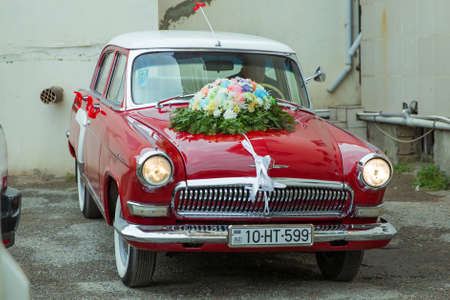 Baku, Azerbaijan. 08.14.2017 .Wedding bouquet on vintage wedding car . Unusual front headlight, old burgundy red car for any purpose . Red vintage wedding car parked .のeditorial素材