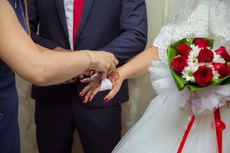 Bridesmaid helps to put a bracelet on his arm for the bride. bride putting on jewelry, focus on bracelet. Close up of groom giving his bride bracelet as symbol of his love on their wedding day.の写真素材