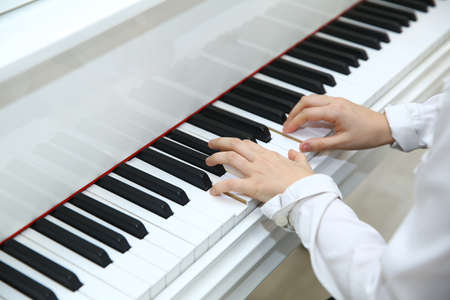 Little boy playing the piano at home . White piano .の写真素材