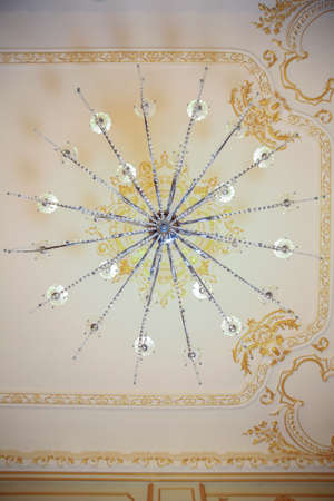 Crystal chandelier view from below . Crystal chandelier with glowing lights photographed from below. A view from below on a rich chandelier hanging from a ceilingの写真素材