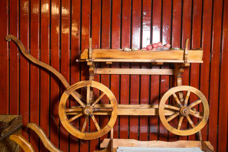 Conservative ancient wagon on white background . Wooden rustic four-wheel cart . onion in wooden cart bags . Wagon wood. Old farm transport. Ancient cargo carriage against a red wooden backgroundの写真素材