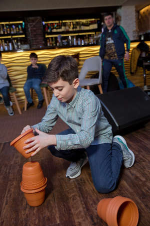 Azerbaijan Baku. 09.03.2020 . children play a race to stack a bowl on top of each other. Kids Playing with white brown cups building a cup tower on floor.のeditorial素材