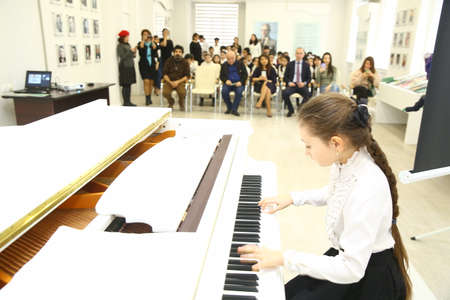 Azerbaijan Baku 21.02.2020 . Little girl playing the piano at home . White piano .のeditorial素材