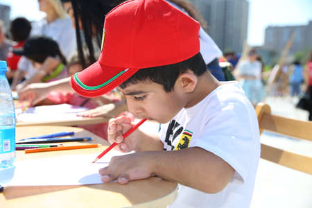 BAKU, AZERBAIJAN - JUNE 1 2019 : Kids festival . In park of Heydar Aliyev Center. Cute little kids drawing pictures and sitting at table, closeupのeditorial素材