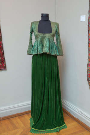 Azerbaijan Baku 04.12.2020 . Ancient national costume of Azerbaijan . Green Woman Arkhalig On the model . Ancient carpet . Sand Bag Saddlebag Design .のeditorial素材