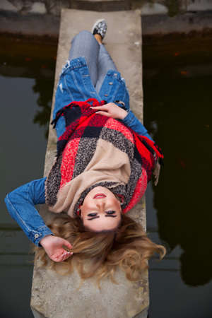 Baku Azerbaijan 21.12.2019 . The girl lies on a rock in the pond and takes a photo and laughs .のeditorial素材