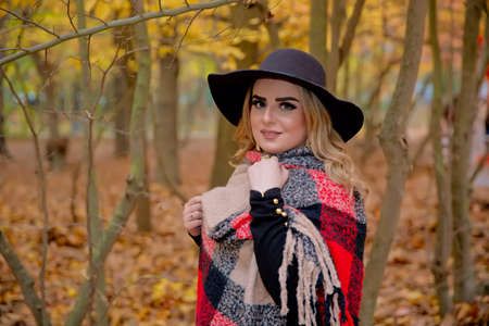 Baku Azerbaijan 21.12.2019 . photo session beautiful girl in the park between the leaves in front of the tree in autumn . The girl in the black hat looks at the camera.のeditorial素材