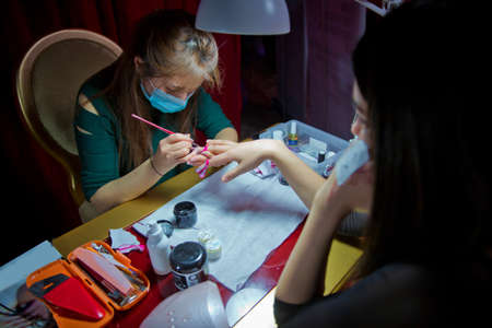 Manicure hands salon . Woman in a nail salon receiving a manicure by a beautician . Manicure process in beautiful salon . Closeup of Woman applying nail varnish to finger nailsのeditorial素材